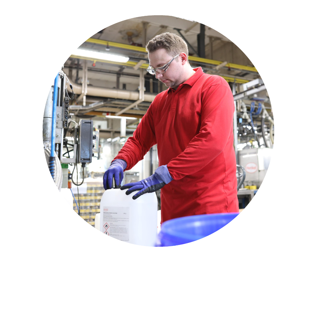 A male Henkel employee filling a plastic container with liquid desinfectant in a production hall