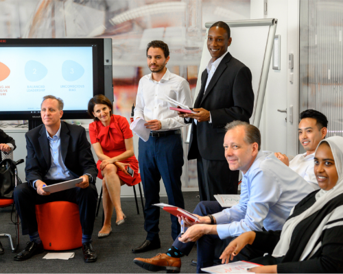 A diverse Henkel team sits together at a workshop and looks in at the speaker