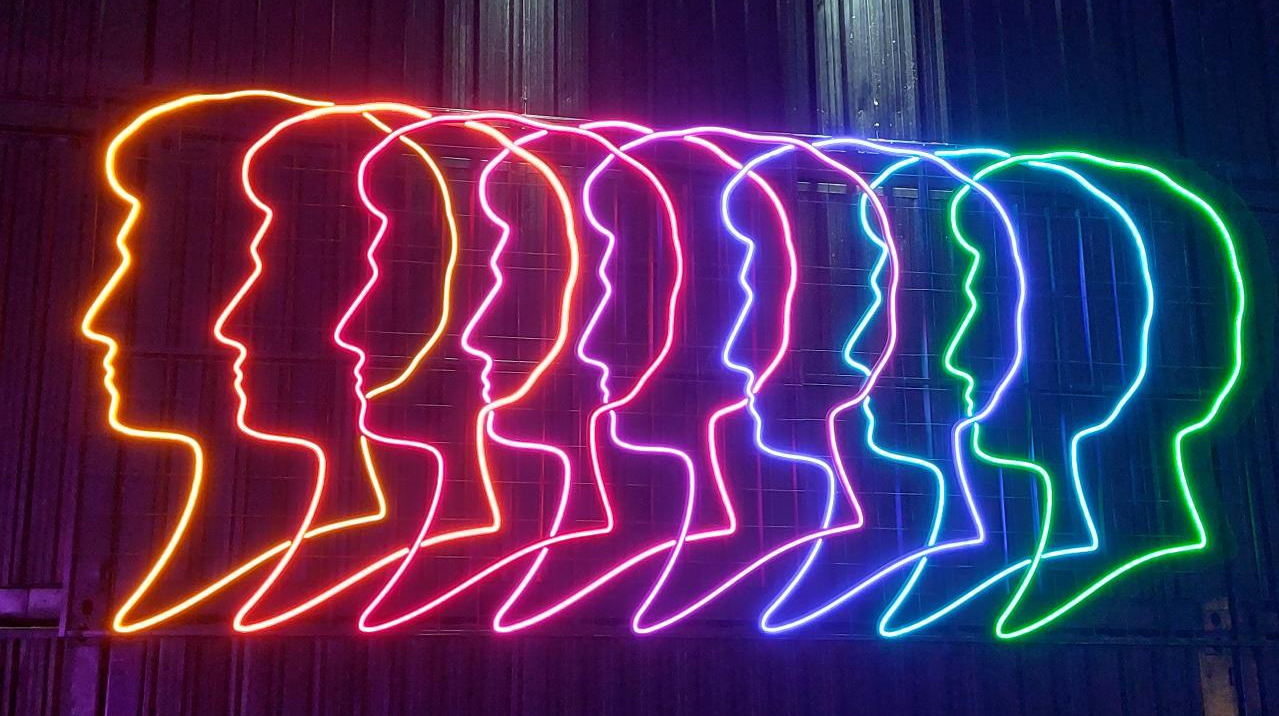 Schwarzkopf head silhouette logo in neon lights with different colours on a wall.