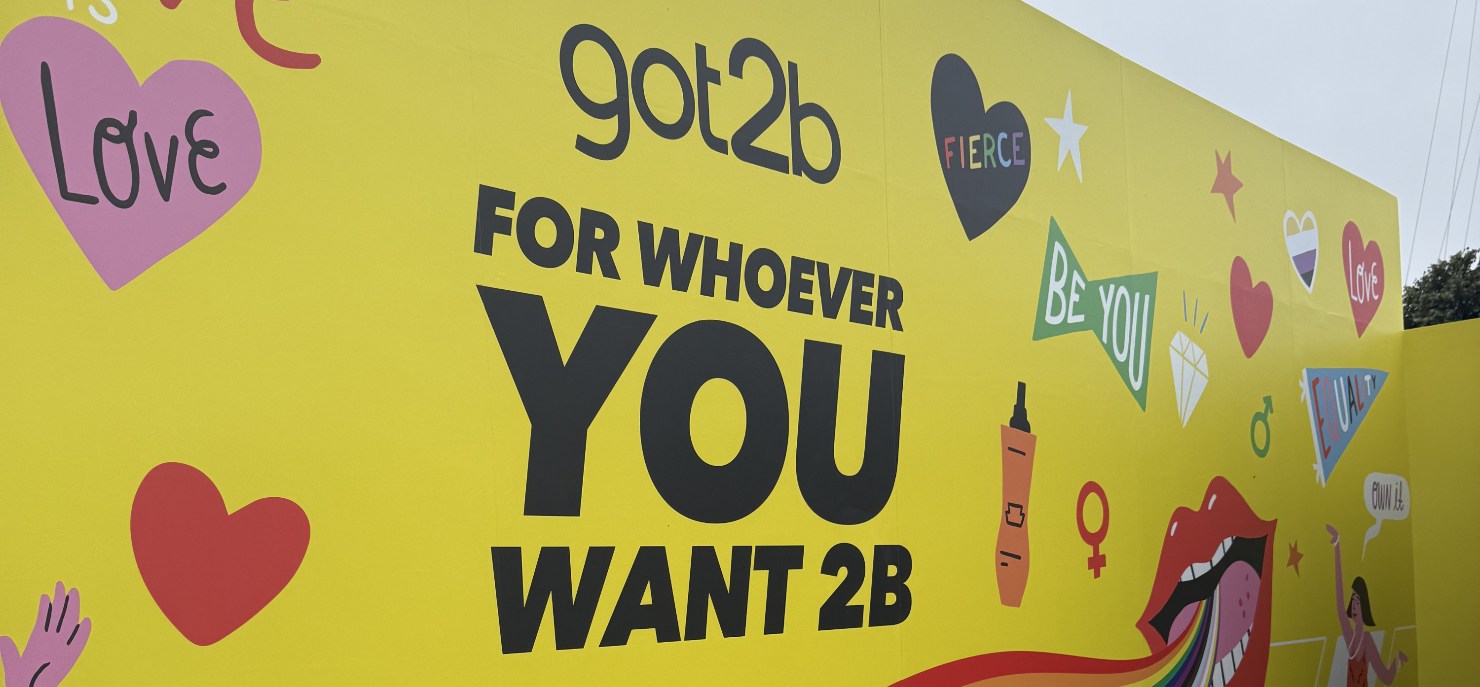 A yellow banner with a rainbow and the phrase “got2b” and “For Whoever You Want 2b”
