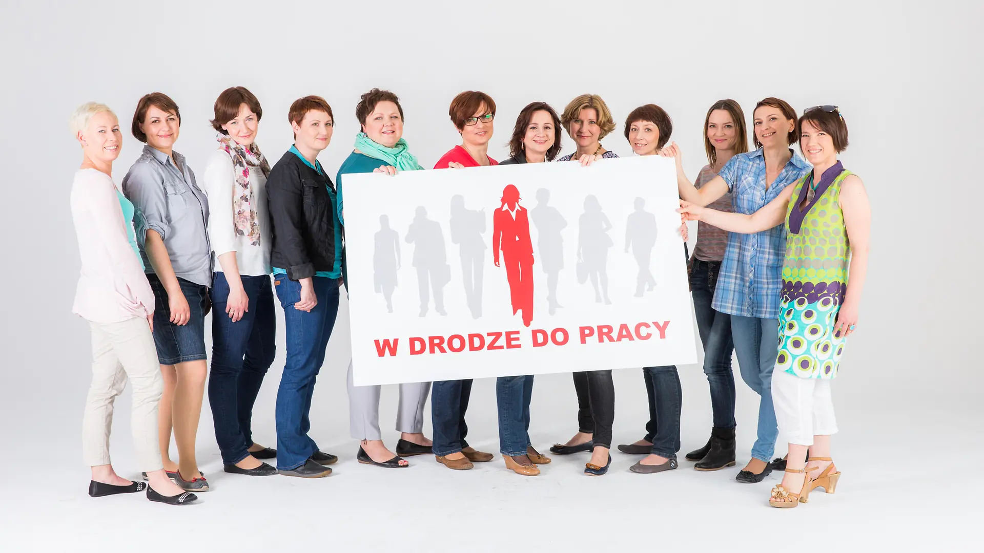 Women standing together with the “W drodze do pracy” sign