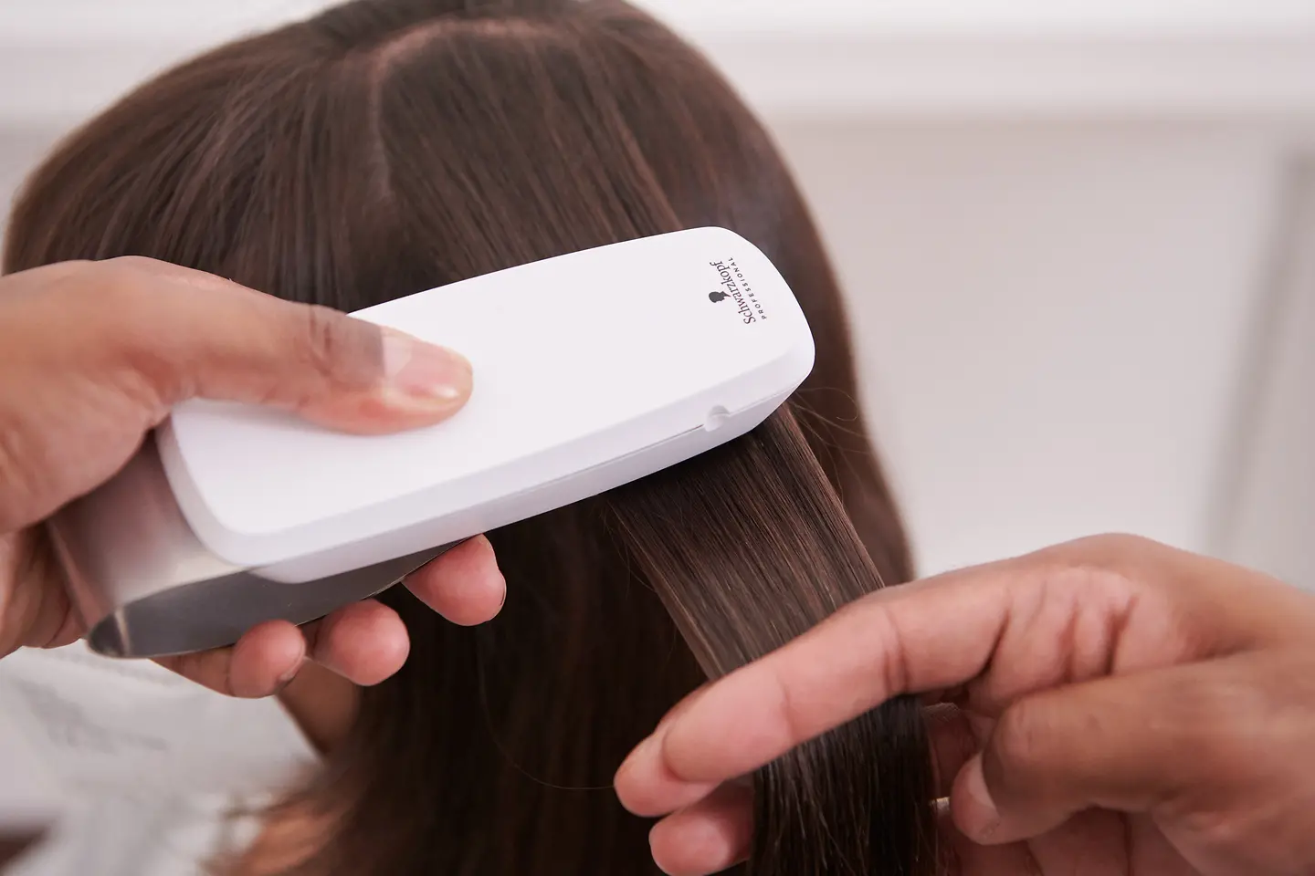 The hairdresser scans the customer's hair with the SalonLab Analyzer.
