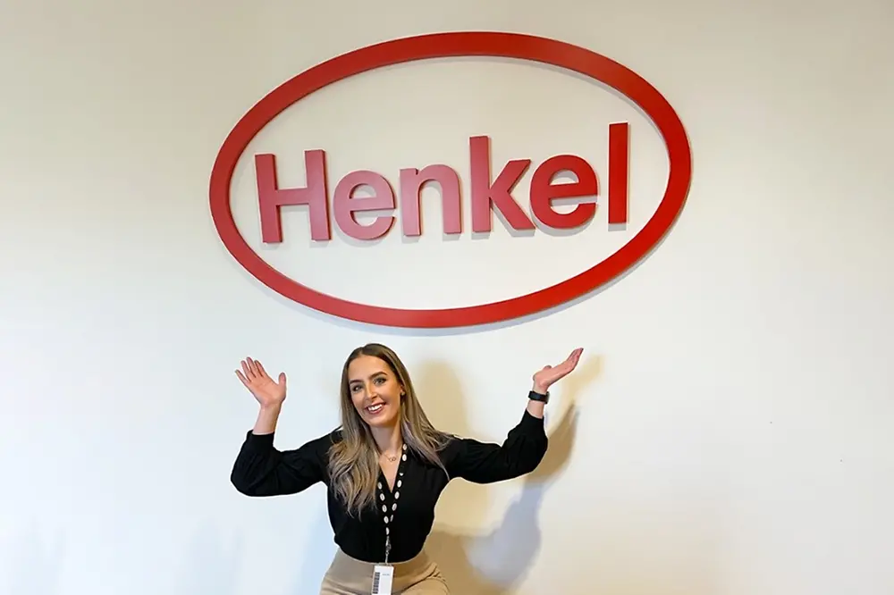 Henkel employee in front of Henkel sign