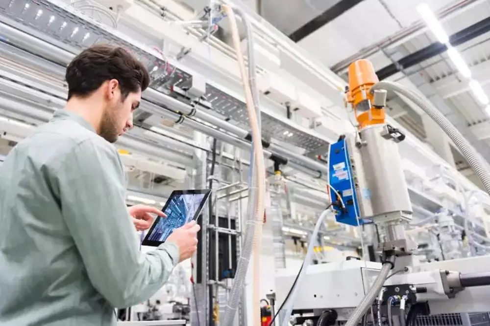 Workers operating machinery inside an industrial manufacturing plant.