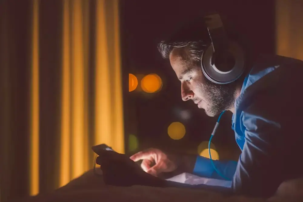 Person wearing headphones working with electronic equipment in a dark environment.