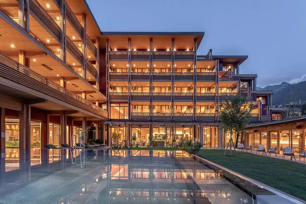 Modern commercial building with illuminated exterior and reflecting pool at dusk.