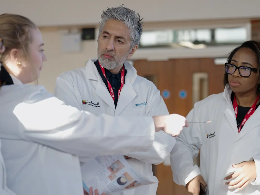 a group in white lab coats stand talking