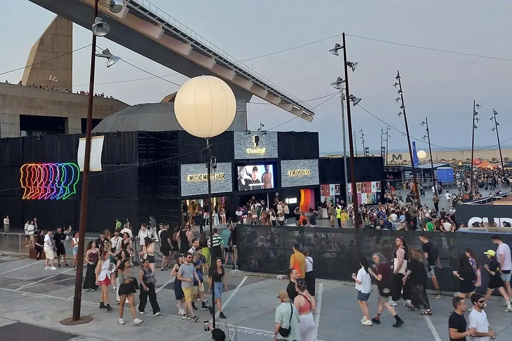 Stage with Schwarzkopf logo at a music festival, with crowds of people.