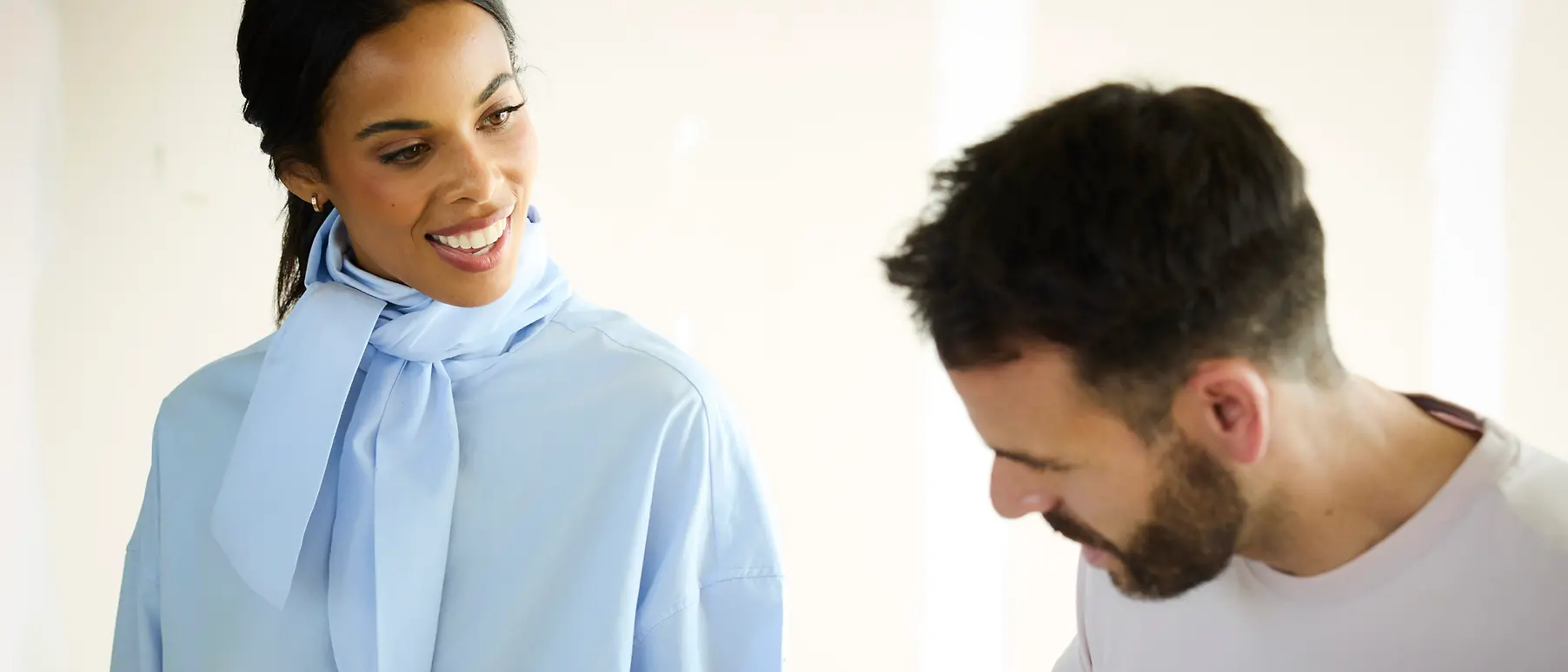 A woman stands next to a man in a fashion show fitting
