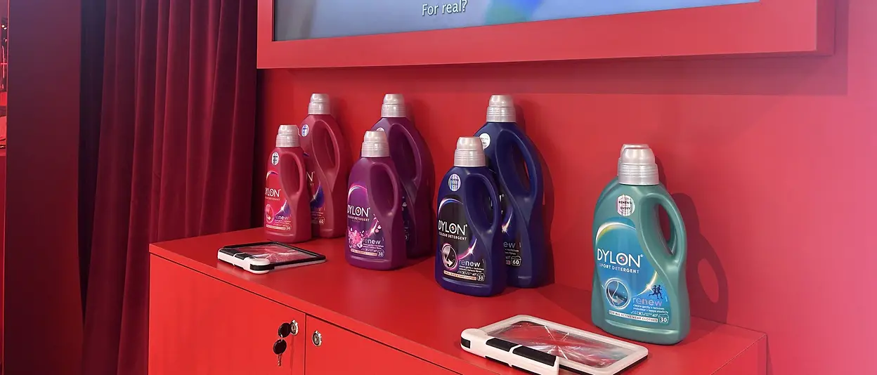 Dylon detergents are on a red table with a screen in the background