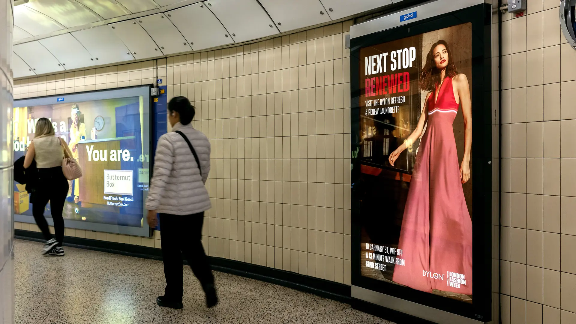 Dylon advertisement on the screen on the London Underground with people passing