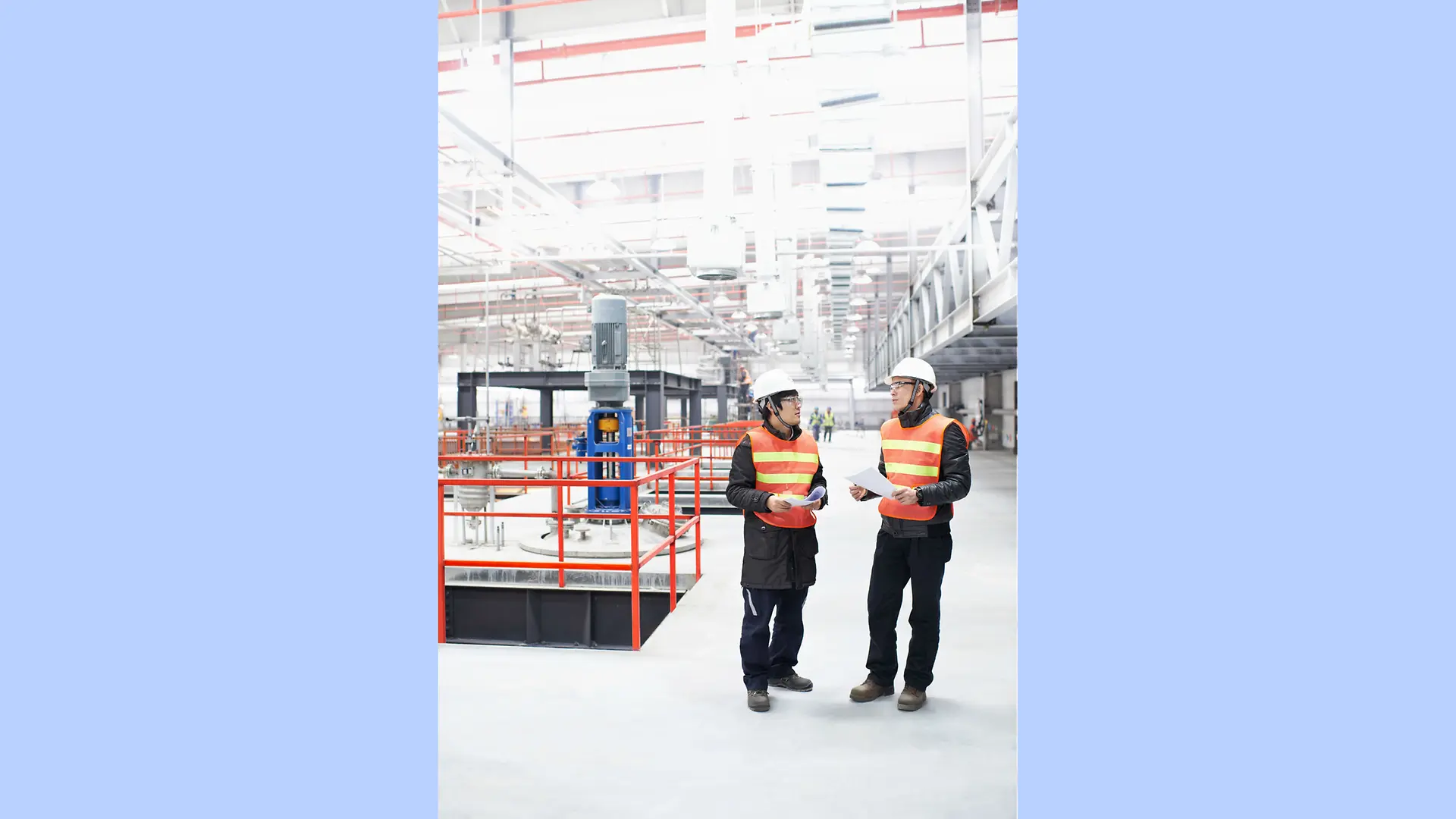 Deux opérateurs de production se tiennent dans une immense usine lumineuse de la Dragon Plant de Henkel en Chine.