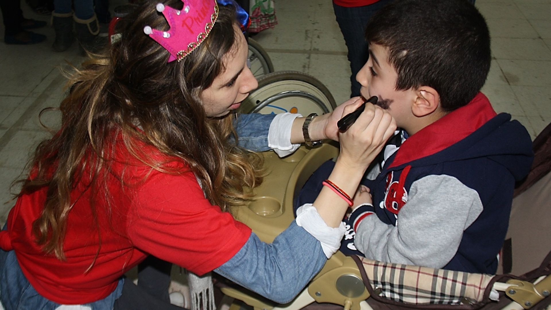 A volunteer princess paints the face of a young boy
