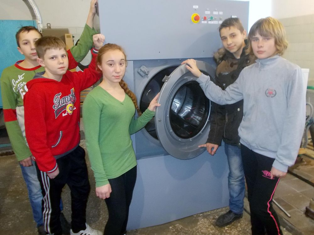 Foster children pose with the donated industrial washing machine
